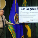 
              Los Angeles County Sheriff Alex Villanueva points to a Los Angeles Times story during a news conference, Tuesday, April 26, 2022, in Los Angeles. Villanueva disputed allegations that he orchestrated a coverup of an incident where a deputy knelt on a handcuffed inmate's head last year. Villanueva, who oversees the nation's largest sheriff's department, also indicated that an Los Angeles Times reporter is under criminal investigation after she first reported the incident with the inmate. (AP Photo/Damian Dovarganes)
            