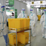
              In this photo released by China's Xinhua News Agency, medical workers in protective suits walk at the Shanghai New International Expo Center, which has been converted to a quarantine facility for people with mild and symptomatic cases of COVID-19, in Shanghai, Friday, April 1, 2022. (Xinhua via AP)
            