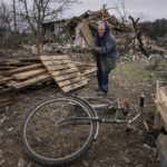 
              A woman collects wooden planks in a street destroyed by shellings in Chernihiv, Ukraine, Wednesday, April 13, 2022. (AP Photo/Evgeniy Maloletka)
            