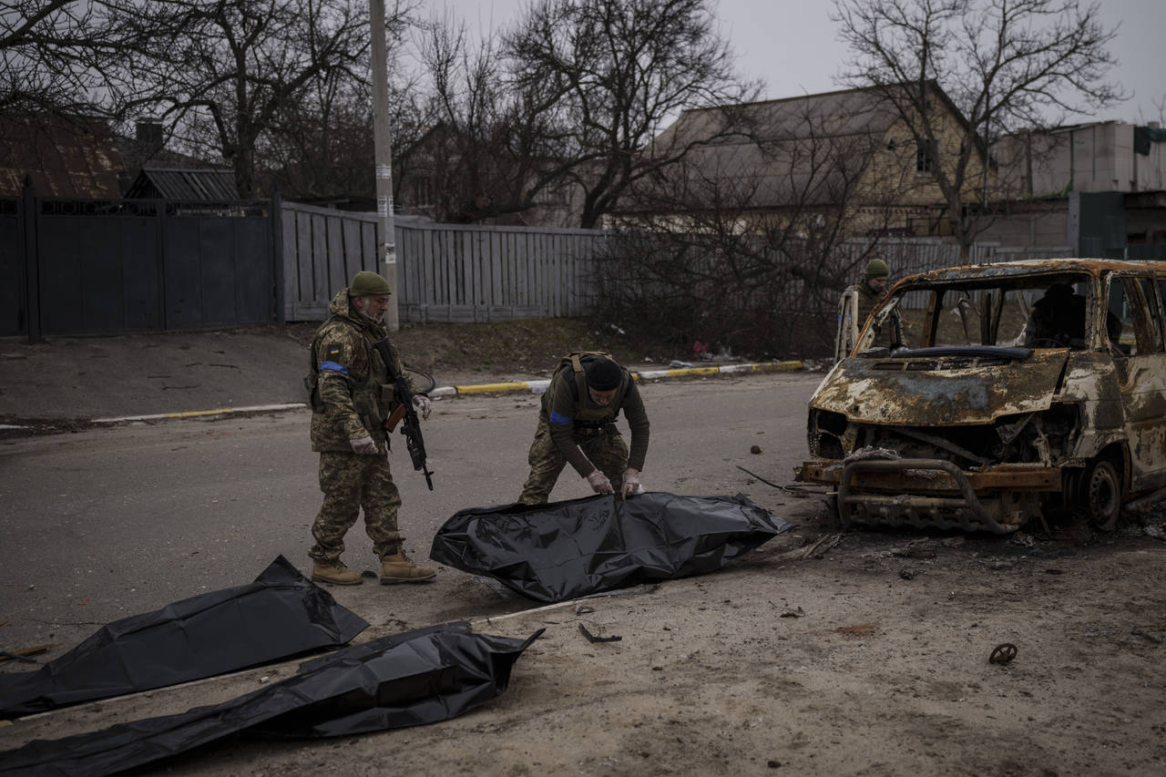 Ukrainian soldiers recover the remains of four killed civilians from inside a charred vehicle in Bu...