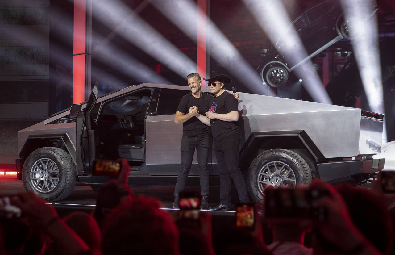 Tesla CEO Elon Musk, right, and vehicle designer Franz von Holzhausen speak at the "Cyber Rodeo" gr...