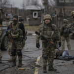 
              Ukrainian servicemen stand while checking bodies of civilians for booby traps, in the formerly Russian-occupied Kyiv suburb of Bucha, Ukraine, Saturday, April 2, 2022. As Russian forces pull back from Ukraine's capital region, retreating troops are creating a "catastrophic" situation for civilians by leaving mines around homes, abandoned equipment and "even the bodies of those killed," President Volodymyr Zelenskyy warned Saturday. (AP Photo/Vadim Ghirda)
            
