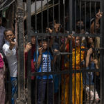 
              Residents shout from behind a bolted iron gate during the demolition of Muslim-owned shops at the site of Saturday's violence in New Delhi's northwest Jahangirpuri neighborhood, in New Delhi, India, Wednesday, April 20, 2022. Authorities riding bulldozers razed a number of Muslim-owned shops in New Delhi before India's Supreme Court halted the demolitions Wednesday, days after communal violence shook the capital and saw dozens arrested. (AP Photo/Altaf Qadri)
            