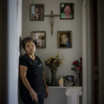 
              Yolanda Bay stands next to a photo of her husband, Luis Alfonso Bay Montgomery, lower right, at their home in San Luis, Ariz., Saturday, March 19, 2022. Montgomery, 59, died from COVID on July 18, 2020. "It's time to get rid of his clothes, but ...," she says, unable to finish the sentence. "There are times that I feel completely alone. And I still can't believe it." (AP Photo/David Goldman)
            