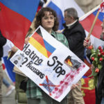 
              "Stop hating Russians" is written on the sign of this participant of a pro-Russian demonstration in Frankfurt, Germany, Sunday, April 10, 2022. The police accompanied the rally with several hundred units. The demonstration was announced under the motto "Against agitation and discrimination of Russian-speaking fellow citizens/Against war - for peace". (Boris Roessler/dpa via AP)
            