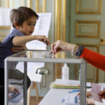 
              A woman and her son cast a ballot during the first round of the French presidential election, in Strasbourg, eastern France Sunday, April 10, 2022. The polls opened at 8am in France for the first round of its presidential election where up to 48 million eligible French voters will be choosing between 12 candidates. (AP Photo/Jean-Francois Badias)
            