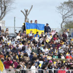 
              People waiting for Pope Francis to arrive at the Granaries to celebrate mass in Floriana, Malta, Sunday, April 3, 2022, display an Ukrainian national flag. Francis opened his second and final day in Malta by visiting the Grotto of St. Paul in Rabat, where the disciple stayed after being shipwrecked en route to Rome in AD 60. (AP Photo/Andrew Medichini)
            