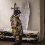 
              Vova, 10, looks as the body of his mother, Maryna, is taken from the morgue before her funeral in Bucha, on the outskirts of Kyiv, Ukraine, on Wednesday, April 20, 2022. Vova's mother died while they sheltered in a cold basement for more than a month during the Russian military's occupation. (AP Photo/Emilio Morenatti)
            