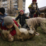 
              Children play with a dog in Bucha, on the outskirts of Kyiv, Ukraine, Friday, April 8, 2022. (AP Photo/Rodrigo Abd)
            