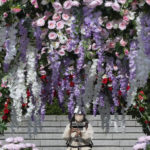 
              A woman wearing a face mask as a precaution against the coronavirus takes pictures of an artificial flower arrangement at a park in Goyang, South Korea, Tuesday, April 19, 2022. (AP Photo/Ahn Young-joon)
            