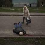 
              A woman walks next to the body of a man killed during a Russian bombardment at a residential neighborhood in Kharkiv, Ukraine, Tuesday, April 19, 2022. Russia ratcheted up its battle for control of Ukraine’s eastern industrial heartland on Tuesday, intensifying assaults on cities and towns along a front hundreds of miles long in what officials on both sides described as a new phase of the war. (AP Photo/Felipe Dana)
            