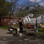 
              A woman hangs out the washing next to her house in Bucha, on the outskirts of Kyiv, on Wednesday, April 27, 2022. (AP Photo/Emilio Morenatti)
            
