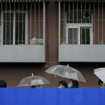 
              Residents holding umbrellas line up in the rain along the barricaded fence for COVID tests outside the locked-down apartment building on Wednesday, April 27, 2022, in Beijing. China employs a variety of metal barricades, metal sheeting and door locks to keep people inside their apartments, buildings or complexes during lockdowns. The barriers have been deployed in multiple cities across China as part of the fight against COVID-19. (AP Photo/Andy Wong)
            