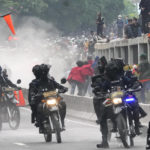 
              Police disperse protesters during a rally in Jakarta, Indonesia, Monday, April 11, 2022. Thousands of students marched in cities around Indonesia on Monday to protest against rumors that the government is considering postponing the 2024 presidential election to allow President Joko Widodo to remain in office beyond the two-term legal limit, calling it a threat to the country's democracy. (AP Photo/Tatan Syuflana)
            