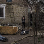 
              Ira Gavriluk holds her cat as she walks among the bodies of her husband, brother, and another man, who were killed outside her home in Bucha, on the outskirts of Kyiv, Ukraine, Monday, April 4, 2022. Russia is facing a fresh wave of condemnation after evidence emerged of what appeared to be deliberate killings of civilians in Ukraine. (AP Photo/Felipe Dana)
            