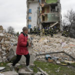 
              A woman carries her belongings as she leaves her house, background, ruined in the Russian shelling in Borodyanka, Ukraine, Wednesday, April 6, 2022. (AP Photo/Efrem Lukatsky)
            