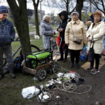 
              Local residents gather near a generator to charge their mobile devices in an area controlled by Russian-backed separatist forces in Mariupol, Ukraine, Friday, April 22, 2022. (AP Photo/Alexei Alexandrov)
            