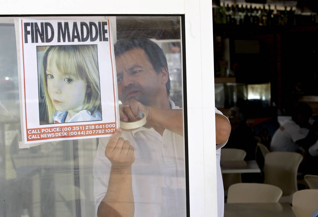 FILE - A waiter hangs a picture of missing 3-year-old girl Madeleine McCann on a restaurant's windo...
