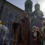 
              Fr. Mykola Ivanov, with an incense burner, leads members of his congregation in the procession of the Holy Shroud on Good Friday at Transfiguration Of Our Lord Ukrainian Catholic Church, in Shamokin, Pa., Friday, April 15, 2022. The Holy Shroud is taken outside around the church to symbolize the funeral procession of Christ to the grave. The Holy Shroud is a cloth depicting the Savior lying in the tomb. (AP Photo/Carolyn Kaster)
            