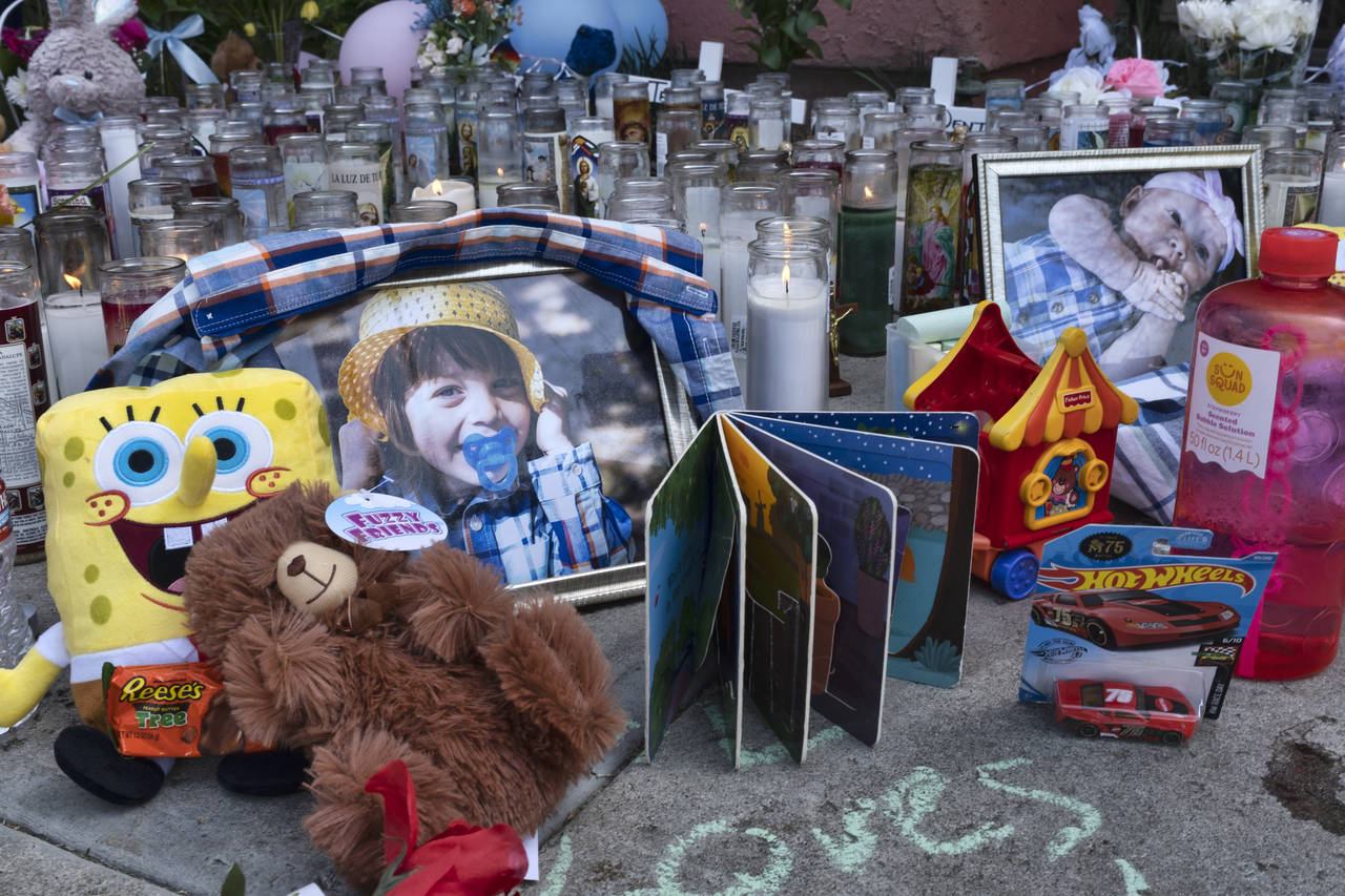 FILE - Photos, candles, flowers and balloons are placed as a memorial for three children who were k...