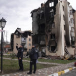 
              Police officers take pictures of buildings damaged by shelling in Irpin, in the outskirts of Kyiv, Ukraine, Monday, April 11, 2022. (AP Photo/Evgeniy Maloletka)
            