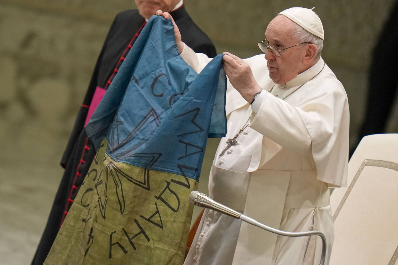 Pope Francis shows a flag that was brought to him from Bucha, Ukraine, during his weekly general au...