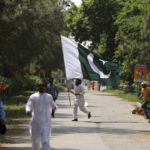 
              A supporter of ruling party Pakistan Tehreek-e-Insaf (PTI) holds the national flag during a protest in Islamabad, Pakistan, Sunday, April 3, 2022. Pakistan's embattled Prime Minister Imran Khan said Sunday he will seek early elections after sidestepping a no-confidence challenge and alleging that a conspiracy to topple his government had failed. (AP Photo/Rahmat Gul)
            