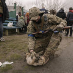 
              A Ukrainian serviceman tries unsuccessfully to convince a puppy to drink milk as residents wait for distribution of food products in the village of Motyzhyn, Ukraine, which was until recently under the control of the Russian military, Sunday, April 3, 2022. (AP Photo/Vadim Ghirda)
            