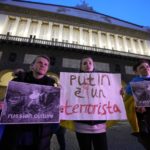 
              People show placards outside the San Carlo opera house in Naples, Monday, April 4, 2022. Placard at center reads in Italian "Putin is a terrorist'. Anastasya Gurskaya, a top ballerina in Kyiv's Opera, who fled the fighting in Ukraine and prima ballerina Olga Smirnova, who quit the Bolshoi last month over the Russian invasion rehearsed on a stage in Naples ahead of a sold-out benefit performance Monday night to raise funds for the Red Cross and champion the cause of peace. (AP Photo/Alessandra Tarantino)
            