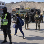 
              A woman walks past Special Forces Police at a checkpoint in the Manchay district, on the outskirts of Lima, Peru, Tuesday, April 5, 2022. Peru’s President Pedro Castillo imposed a tight curfew on the capital and the country’s main port in response to sometimes violent protests over rising prices of fuel and food, requiring people in Lima and Callao to mostly stay in their homes all of Tuesday. (AP Photo/Martin Mejia)
            