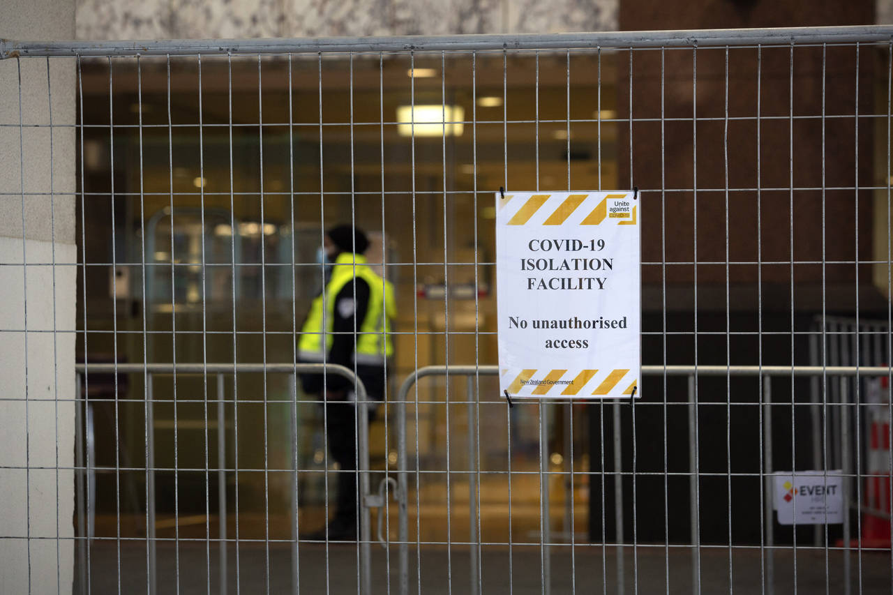 A security worker stands behind a fence at the Crowne Plaza Hotel that is used as a quarantine faci...