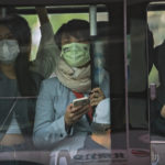 
              Commuters wearing face masks to help protect from the coronavirus look out from a crowded traveling bus during the morning rush hour, Monday, April 18, 2022, in Beijing. (AP Photo/Andy Wong)
            