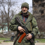 
              An armed serviceman of Donetsk People's Republic militia patrols a street in an area controlled by Russian-backed separatist forces in Mariupol, Ukraine, Friday, April 15, 2022. Mariupol, a strategic port on the Sea of Azov, has been besieged by Russian troops and forces from self-proclaimed separatist areas in eastern Ukraine for more than six weeks. (AP Photo/Alexei Alexandrov)
            