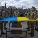 
              Soldiers place the Ukrainian flag on the coffin of 41-year-old soldier Simakov Oleksandr, during his funeral ceremony, after after he was killed in action, at the Lychakiv cemetery, in Lviv, western Ukraine, Monday, April 4, 2022. (AP Photo/Nariman El-Mofty)
            