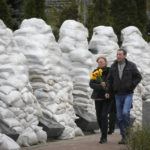 
              People pay respect to the Chernobyl firefighters at a memorial in capital Kyiv, Ukraine, Tuesday, April 26, 2022. At left, firefighter sculptures are covered with bags to protect against the Russian shelling. April 26 marks the 36th anniversary of the Chernobyl nuclear disaster. A reactor at the Chernobyl nuclear power plant exploded on April 26, 1986, leading to an explosion and the subsequent fire spewed a radioactive plume over much of northern Europe. (AP Photo/Efrem Lukatsky)
            