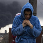 
              A woman walks as smoke rises in the air in the background after shelling in Odesa, Ukraine, Sunday, April 3, 2022. (AP Photo/Petros Giannakouris)
            