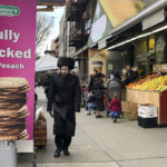 
              A man walks in front of a kosher supermarket in the Hasidic Jewish section of Brooklyn’s Williamsburg neighborhood in New York next to a billboard celebrating the Passover holiday and announcing the unleavened bread known as matzo on April 19, 2022. Some U.S. Jewish families observing the Passover are struggling to pay for matzo, eggs and gefilte fish and worry about how soaring inflation is driving up prices during one of the most important holidays for Jews. (AP Photo/Luis Andres Henao)
            