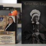 
              A picture of Mother Mary Lange, the founder of the order of the Oblate Sisters of Providence (OSP), is seen next to a card of Sister Delphine Okoro, a nun with the Oblate Sisters of Providence, in a fifth grade classroom at Mother Mary Lange Catholic School in Baltimore, Wednesday, April 27, 2022. (AP Photo/Jacquelyn Martin)
            