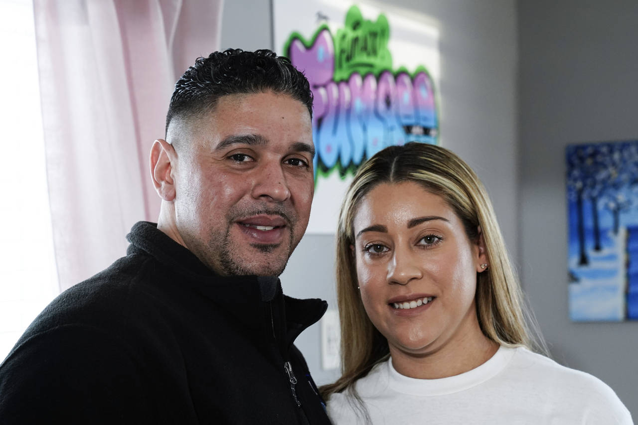 Eladio and Melissa Guzman pose for photographs, Monday, April 4, 2022, in Hicksville, N.Y. The coup...