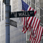 
              FILE - The Wall St. street sign is framed by the American flags flying outside the New York Stock exchange, Friday, Jan. 14, 2022, in the Financial District.  Stocks are opening higher on Wall Street, Thursday, April 28,  as a number of technology companies claw back some of the ground they had lost recently.  (AP Photo/Mary Altaffer, File)
            