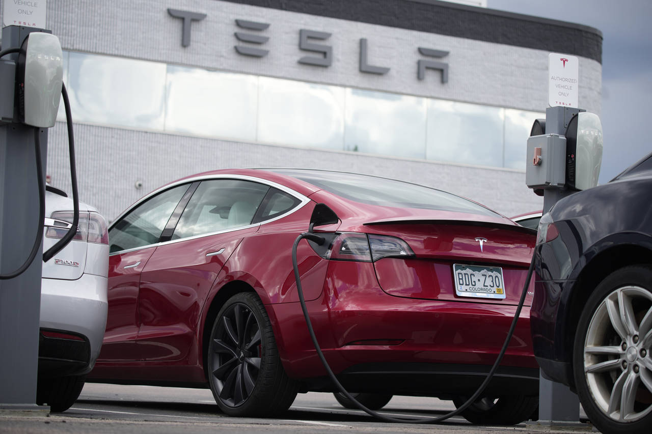 FILE - A 2021 Tesla Model 3 sedan sits in a near-empty lot at a Tesla dealership in Littleton, Colo...