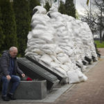 
              A clean-up veteran pays respect to the Chernobyl firefighters at a memorial in capital Kyiv, Ukraine, Tuesday, April 26, 2022. At right, firefighter sculptures are covered with bags to protect against the Russian shelling. April 26 marks the 36th anniversary of the Chernobyl nuclear disaster. A reactor at the Chernobyl nuclear power plant exploded on April 26, 1986, leading to an explosion and the subsequent fire spewed a radioactive plume over much of northern Europe. (AP Photo/Efrem Lukatsky)
            