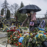 
              Tetiana Rurak, 25-year-old widow Oleksandra Rurak, visits her soldier husband Volodymyr Rurak's, grave with her one and a half year old daughter, after he was killed in action, at the Lychakiv cemetery, in Lviv, western Ukraine, Tuesday, April 5, 2022. (AP Photo/Nariman El-Mofty)
            