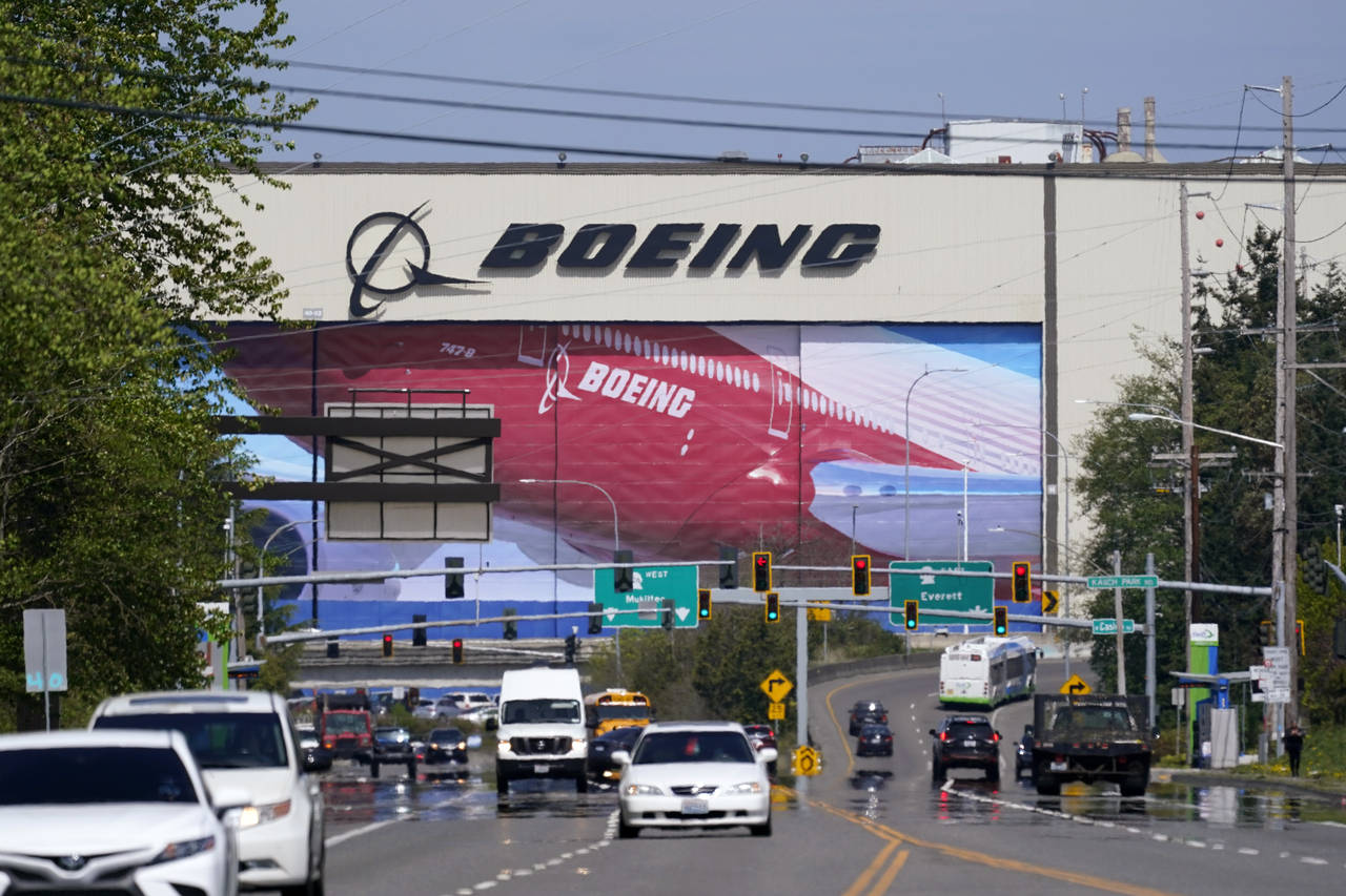 FILE - Traffic drives in view of a massive Boeing Co. production plant, where images of jets decora...