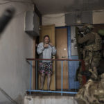 
              FILE - A woman looks as Security Service of Ukraine (SBU) servicemen enter a building during an operation to arrest suspected Russian collaborators in Kharkiv, Ukraine, Thursday, April 14, 2022. Ukrainian authorities are cracking down on anyone suspected of aiding Russian troops under laws enacted by Ukraine’s parliament and signed by President Volodymyr Zelenskyy after the Feb. 24 invasion. Offenders face up to 15 years in prison for acts of collaborating with the invaders or showing public support for them. (AP Photo/Felipe Dana, File)
            