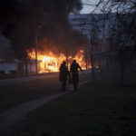
              A couple of residents walk past burning shops after a Russian attack in Kharkiv, Ukraine, Monday, April 11, 2022. (AP Photo/Felipe Dana)
            