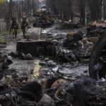 
              Soldiers walk amid destroyed Russian tanks in Bucha, in the outskirts of Kyiv, Ukraine, Sunday, April 3, 2022. Ukrainian troops are finding brutalized bodies and widespread destruction in the suburbs of Kyiv, sparking new calls for a war crimes investigation and sanctions against Russia. (AP Photo/Rodrigo Abd)
            