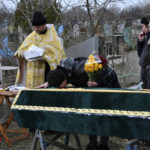 
              Relatives and friends stands by the coffin of Ukrainian serviceman Anatoly German during a funeral ceremony in Kramatorsk, Ukraine, Tuesday, April 5, 2022. Anatoly German was killed during fightings between Russian and Ukrainian forces near the city of Severodonetsk. He leaves a wife, daughter Adelina, 9, son Kirill, 3. (AP Photo/Andriy Andriyenko)
            