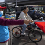 
              A crossing guard wearing a face mask directs a bicyclist at an intersection in Beijing, Tuesday, April 12, 2022. The U.S. has ordered all non-emergency consular staff to leave Shanghai, which is under a tight lockdown to contain a COVID-19 surge. (AP Photo/Mark Schiefelbein)
            