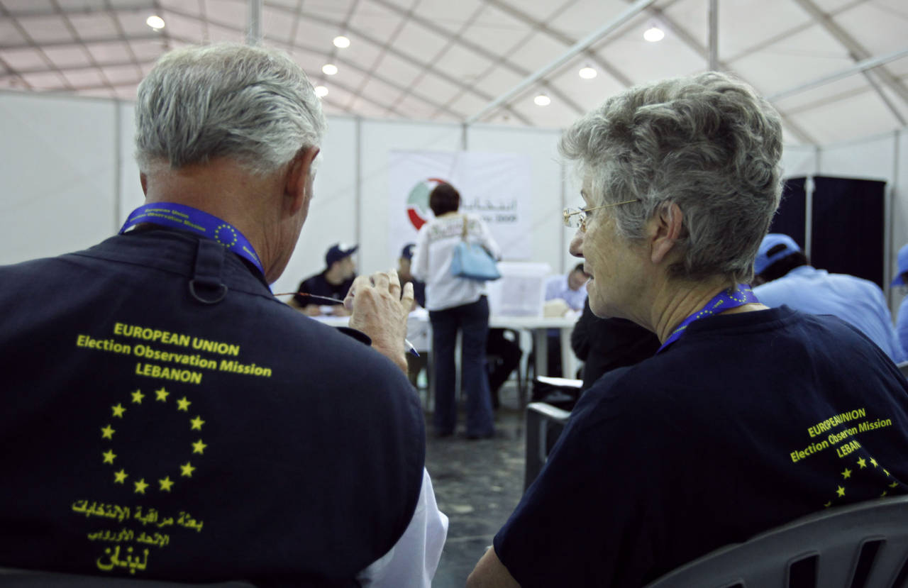 FILE - Two European Union election observers watch as an election worker casts her ballot in early ...